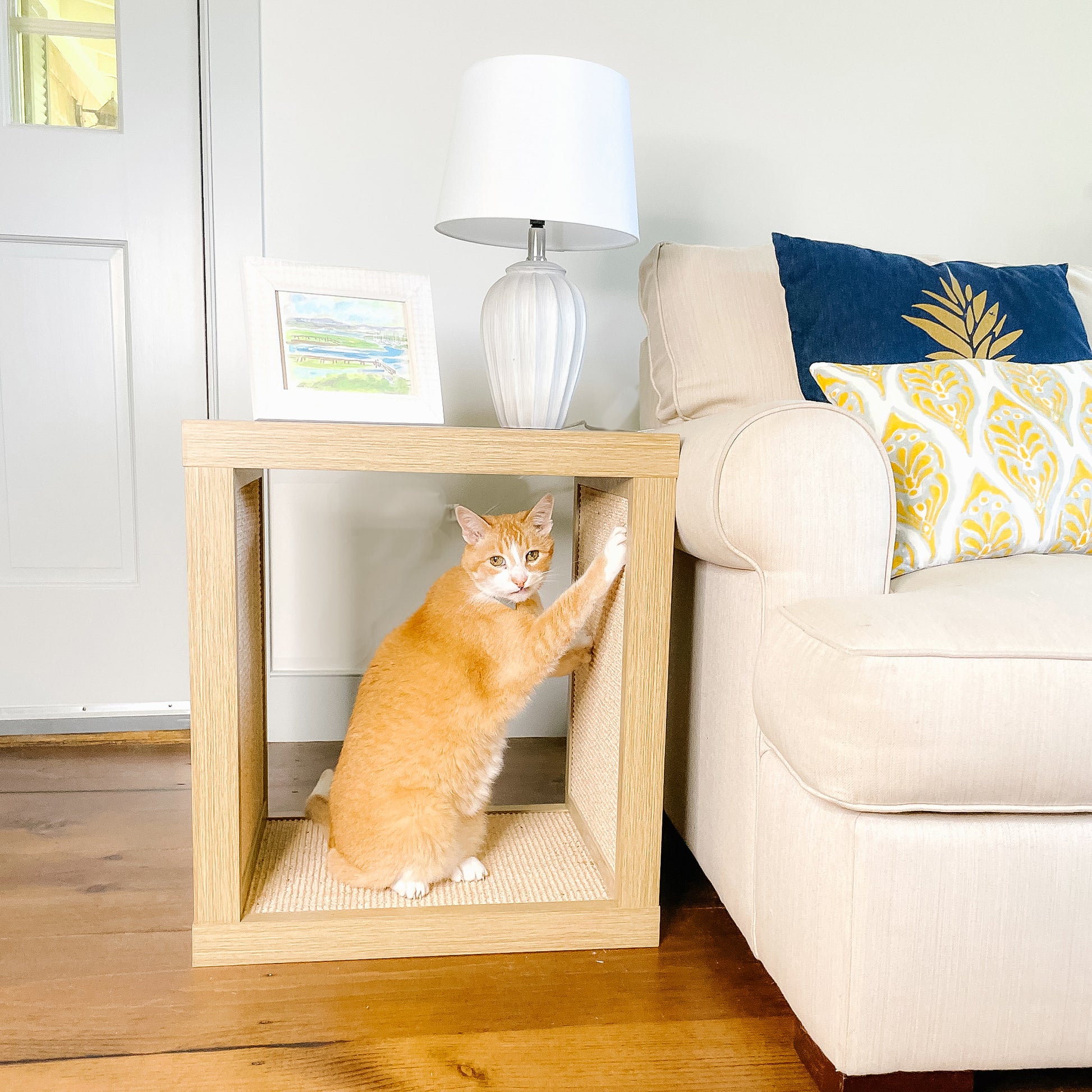 cat scratching on light wood cat scratcher end table next to couch